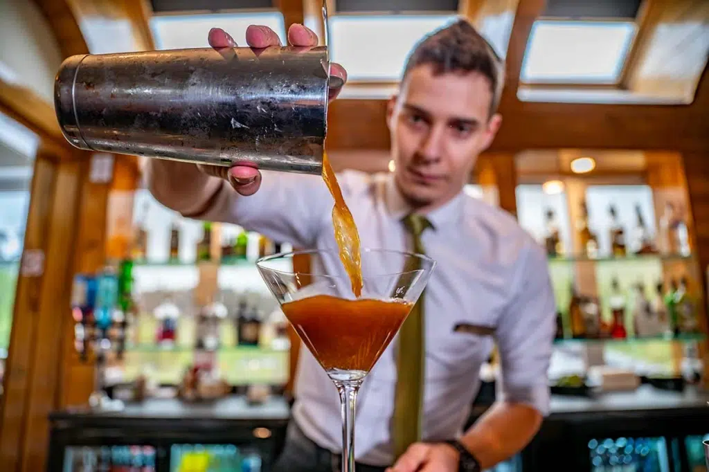 bartender pouring cocktail at restaurant