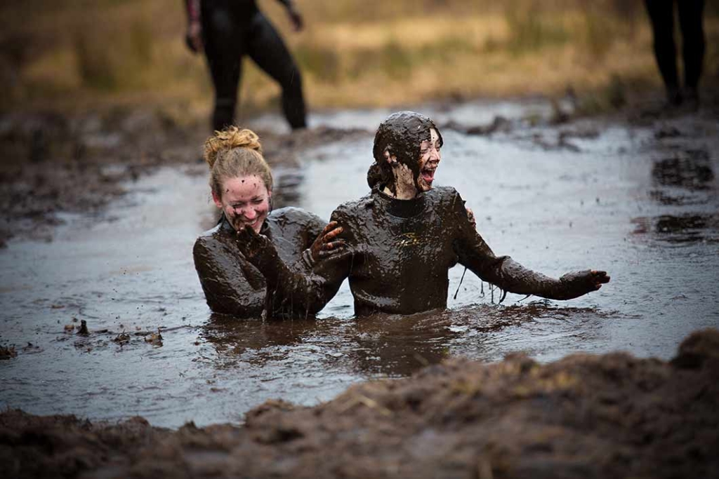 two women laughing in the mud