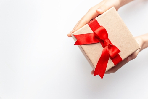 Hands,Holding,A,Gift,Box,With,Red,Ribbon,On,White